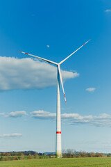 A field of wind turbines generating energy standing in a green field. Wind turbines in a yellow...