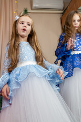 Little girls in festive dress dancing near christmas tree at home
