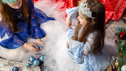 Christmas time, cute children play cuddling and having fun sitting on the floor near the festive Christmas tree