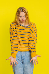 Upset frustrated annoyed Caucasian blonde woman in blouse raising hands in indignant expression,...
