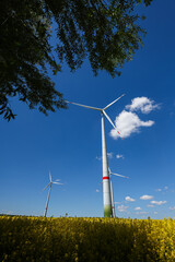 Large windmill turbines in a field with blue sky. Windmill field in the countryside in Europe.