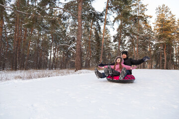 Father and daughter having fun with snow tube in the forest
