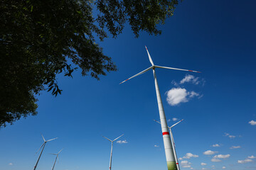 A field of wind turbines generating energy standing in a green field. Wind turbines in a yellow...