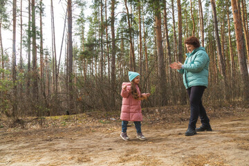 Grandmother with granddaughter walking in nature in the forest