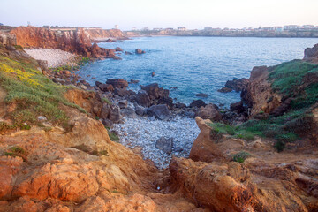 Sunny rocky coastline of Atlantic Ocean in the rays of setting sun, Papoa Island, Peniche, Portugal