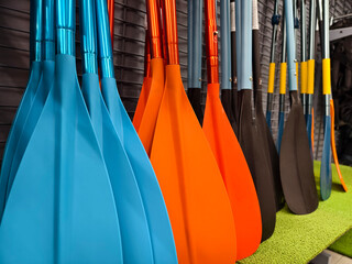 A collection of oars is lined up neatly in a row for use