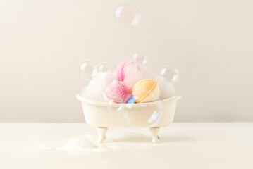 Mini Bathtub with Colorful Handmade Bath Bombs, Foam and Bubbles on Light Background - Spa Concept