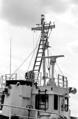 Vintage ship mast with radar and ladder reaching for cloudy sky
