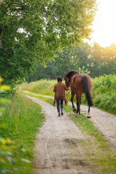 Woman walking with a horse on a path