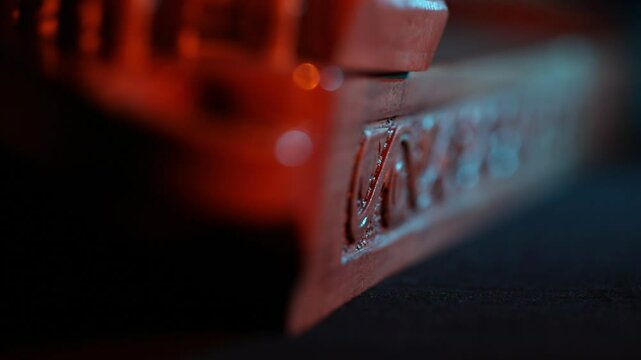 Cinematic macro close-up of a traditional wooden stringed instrument. Slow focus pull along tuning pegs and strings under dramatic red and teal lights, creating a moody atmosphere.
