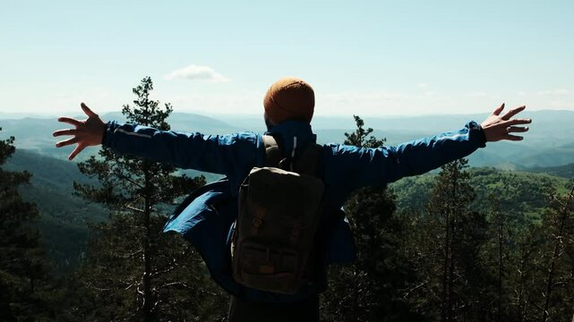 Male hiker with raised arms celebrating at the summit of Tornik mountain in Zlatibor, Serbia, under a bright blue spring sky. Solo travel concept. Horizontal 4k footage