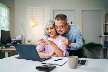 Senior Asian Couple Enjoying Retirement Planning Online Together at Home Using Laptop Computer Searching for Investment Ideas and Financial Security