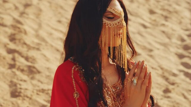 woman dancer in red gold oriental abaya dress dancing waving hands black hair sand desert. Art sexy girl arab style fashion model posing beauty face hides golden mask burka. Arabic nature Dubai UAE