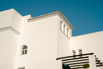 Modern white architecture of a building against a clear blue sky in a sunny location during the day