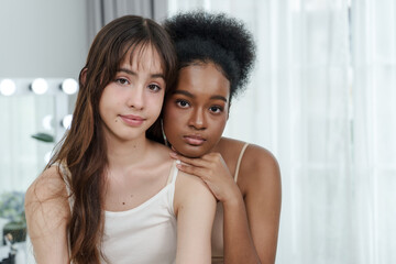 young caucasian female resting head on shoulder of young african female expressing strong emotional friendship diversity gentle connection peaceful love and quiet happiness in natural lighting