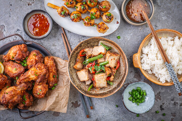 Assortment of Asian street food, stir fry with vegetables, chicken wings, meat balls and rice