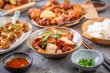 Assortment of Asian street food, stir fry with vegetables, chicken wings, meat balls and rice
