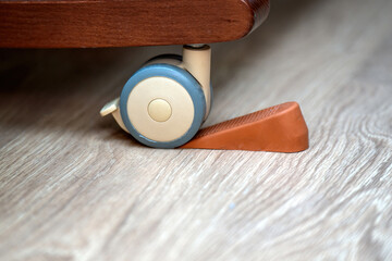 Extra rubber stopper placed under a crib wheel with engaged internal brake for added safety and stability