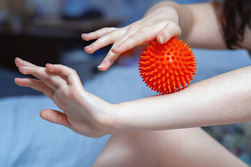 Young woman self-massaging her feet with a red spiky rubber ball for relaxation and muscle relief