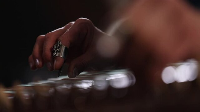 close-up shows a woman's hands playing an ornate wooden zither with plectrums. A microphone captures the beautiful sound of this traditional Middle Eastern folk instrument.