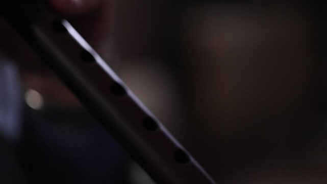Close-up on a musician's hands preparing to play a traditional woodwind instrument, possibly a duduk. He places it on a music stand and adjusts his fingering.