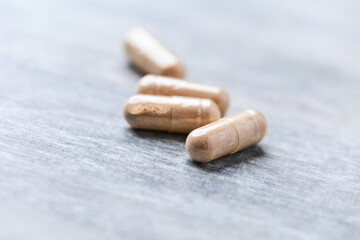 Reishi capsules. Concept for a healthy dietary supplementation. Wooden background. Soft focus. Close up.	