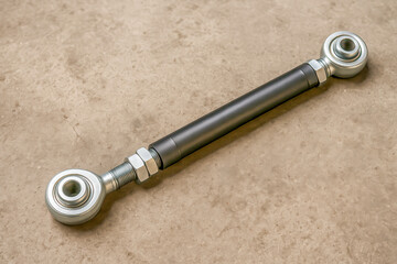 Adjustable rear suspension control arm lying on a concrete floor