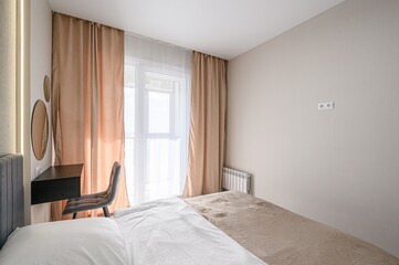 cozy bedroom with a bed, a chair, and curtains. The room is painted in neutral tones, and the natural light streams in through the window