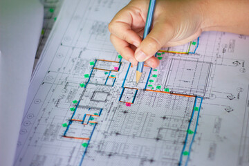Civil Engineer Reviewing Detailed Building Layout with Hand on Blueprint