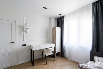 modern bedroom corner features a white desk, fuzzy chair, wall art, window with curtains, and wood floors in a minimalist design