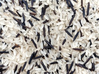 Background view of a mix of uncooked parboiled long-grain rice and wild rice, showcasing a contrast between light beige and dark brown grains.