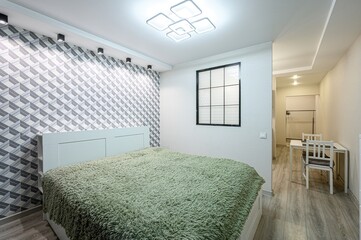 cozy bedroom features a green shag rug, geometric wallpaper, and a window. A dining table with...