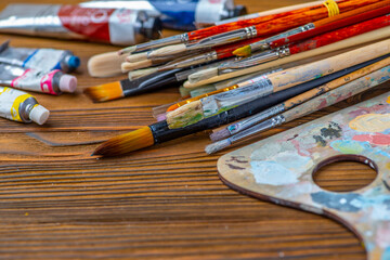 Obraz premium Old used brushes in an artist's studio, a palette with multi-colored spots of oil or acrylic paint
