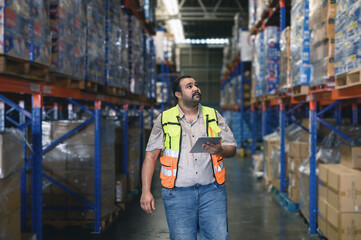Industry warehouse managers in safety uniforms check the stock order details and goods supplies with digital tablets in Logistic center. industry logistic export import distribution concept.