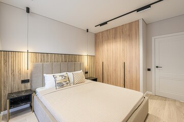 modern bedroom with a large bed, wooden accent wall, wardrobe, and sleek lighting. Neutral colors...