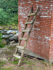 Rustic Wooden Ladder Leaning Against Aged Brick Wall in Nature