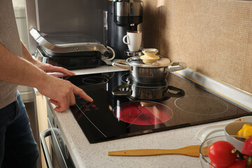 The man turns on the electric stove in the kitchen to cook breakfast.