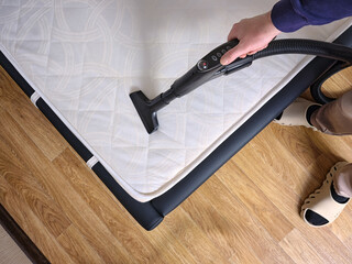 Top view a man disinfecting mattress with vacuum cleaner in bedroom.