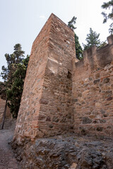 Corner tower of the Alcazaba of Málaga, built with layered brick and stone, standing tall as a reminder of Moorish defensive strength.