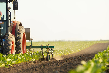 A close-up view shows detailed equipment on a tractor as it cultivates soil, emphasizing modern agricultural methods in farming. © Dejan