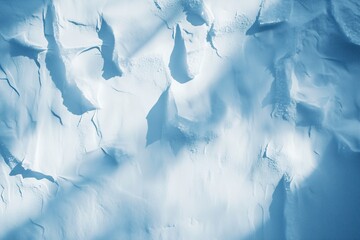 Aerial view of snowy mountain terrain with dramatic shadows and textures