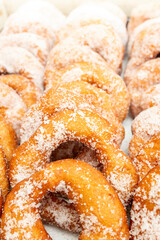 Doughnuts rows powdered with coarse crystal sugar, soft focus close up side view