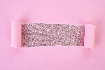 Ripped pink paper copy space revealing pink glitter, bohemian cosmetic backdrop, soft focus close up