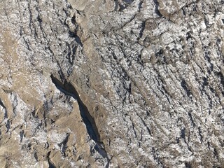 Extreme close up aerial view of a glacier's surface, highlighting intricate patterns of ice and rock formations