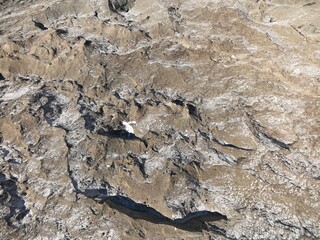 Close up aerial view of a glacier's surface, revealing intricate textures of ice, snow, and rock formations