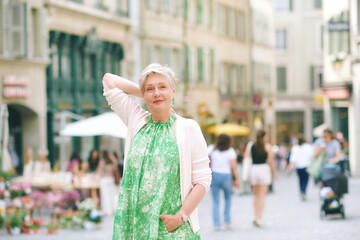 Outdoor portrait of beautiful 55 -60 year old woman posing with city background, fashion and helthy lifestyle
