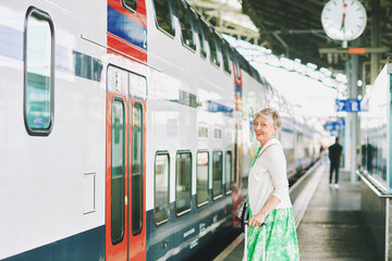 Outdoor portrait of 55 - 60 year old woman at the train station, vacation and active lifestyle