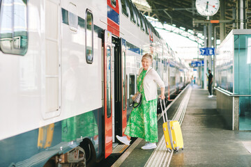 Outdoor portrait of 55 - 60 year old woman at the train station, vacation and active lifestyle