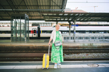Outdoor portrait of 55 - 60 year old woman at the train station, vacation and active lifestyle, image taken in lausanne, Switzerland