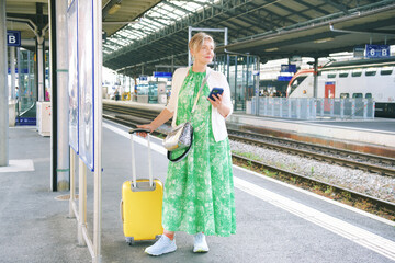 Outdoor portrait of 55 - 60 year old woman at the train station, vacation and active lifestyle